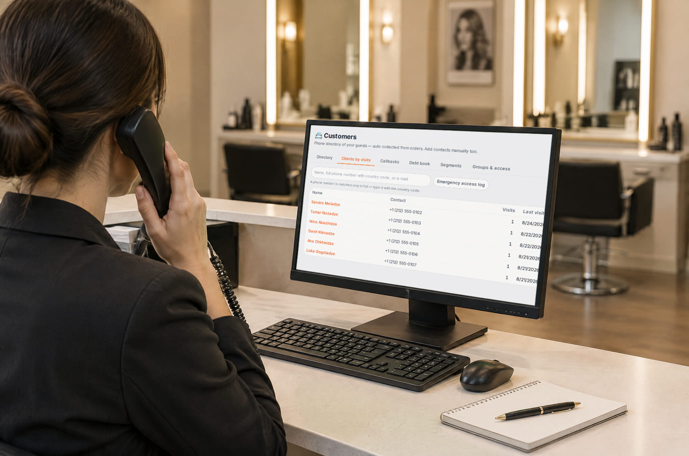 Salon receptionist on a phone call finding the caller in the client list on the monitor